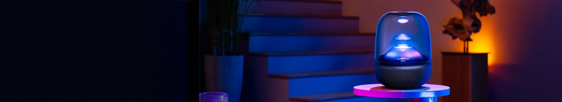 어두운 조명 아래 흰색 테이블 위에 놓여진 하만카돈 AURA STUDIO 5