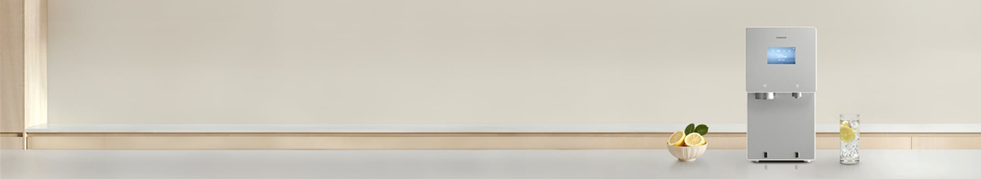 회색톤의 대리석 주방 상판 위에 2026 Bespoke AI 얼음정수기 신제품이 놓여져 있고 제품 좌측에 레몬이 담긴 그릇, 우측에는 레몬과 얼음물이 담긴 컵이 놓여있는 이미지 