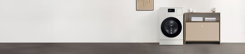 흰 벽 앞에 Bespoke AI 콤보가 있으며 왼쪽에는 액자와 오른쪽에는 베이지색 수납장이 있는