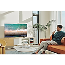 TV 가 선반위에 놓여있습니다. 사용자가 소파에 앉아 TV 를 보고 있고 화면에는 푸른 바다가 보입니다.
