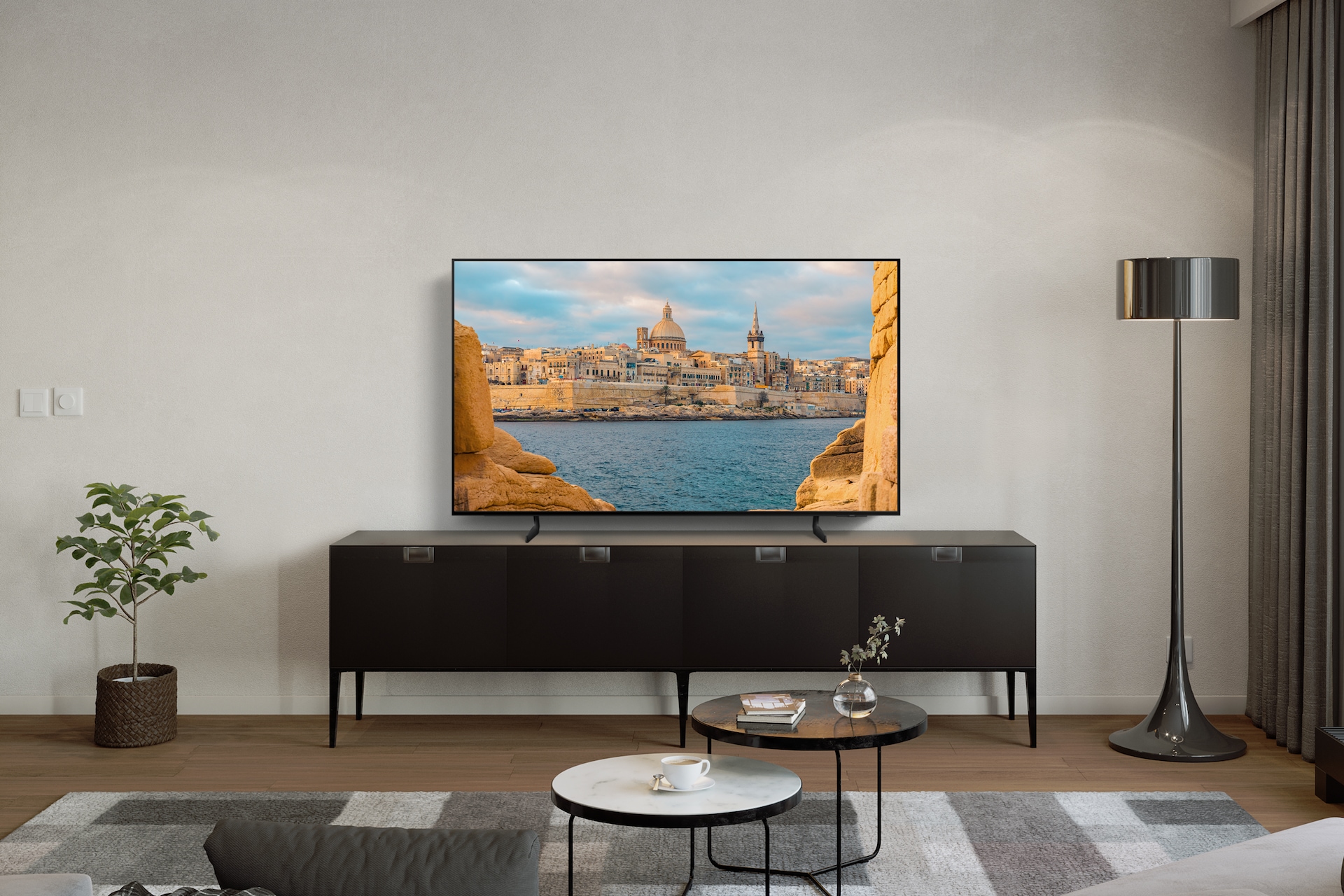 거실의 TV 장 위에 2024 OLED SD85 (194cm) 스탠드형 가 배치되어 있고 TV장 앞에는 원탁이 있습니다.