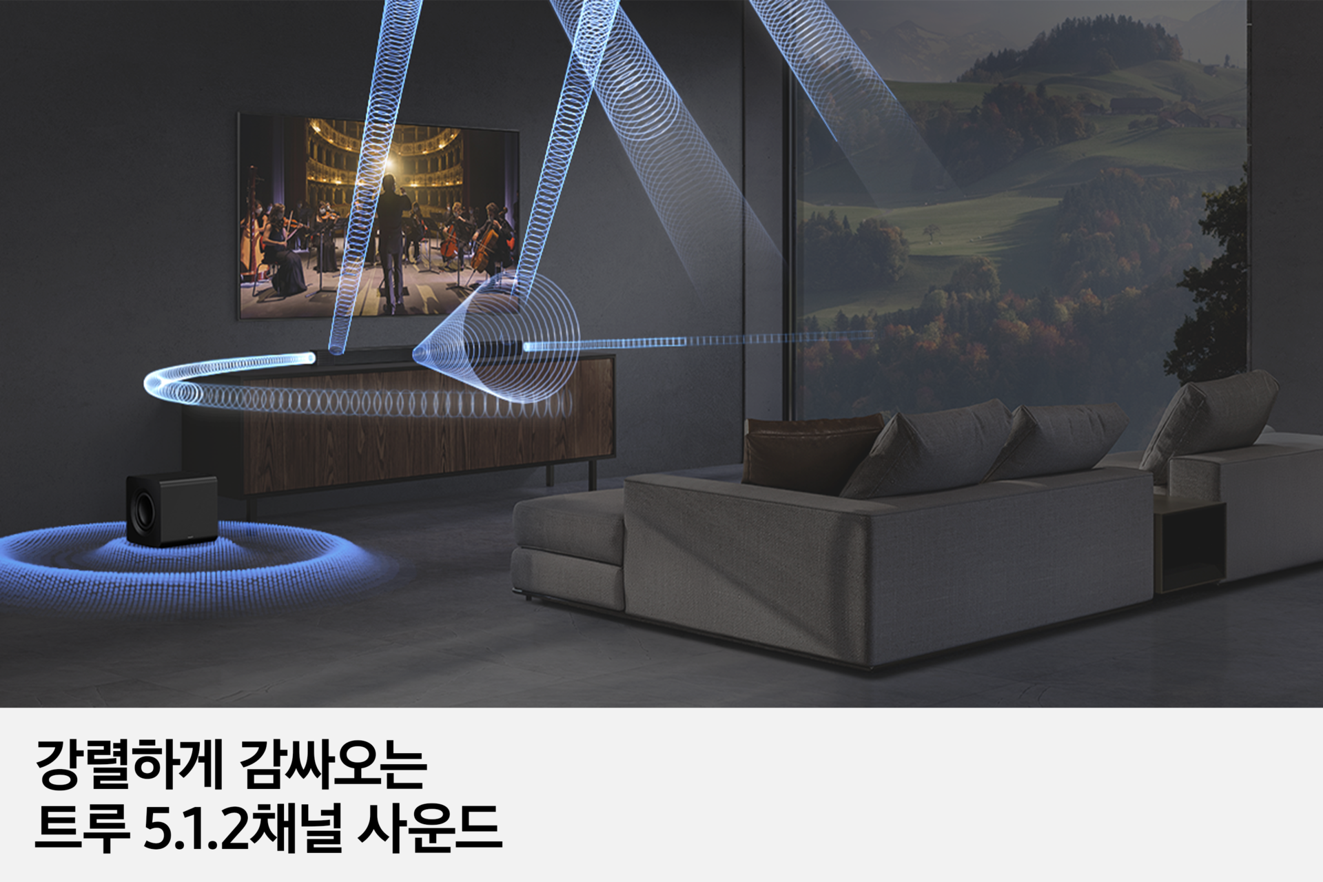 거실 벽에 TV가 설치되어 있습니다. TV 하단에는 장식장이 놓여 있으면 사운드바가 놓여 있으며, 우측 하단에는 서브우퍼가 놓여 있습니다. 사운드바와 서브우퍼에서는 음향효과가 나오고 있습니다. 이미지 하단에는 '강렬하게 감싸오는 트루 5.1.2채널 사운드' 문구가 기재되어 있습니다.