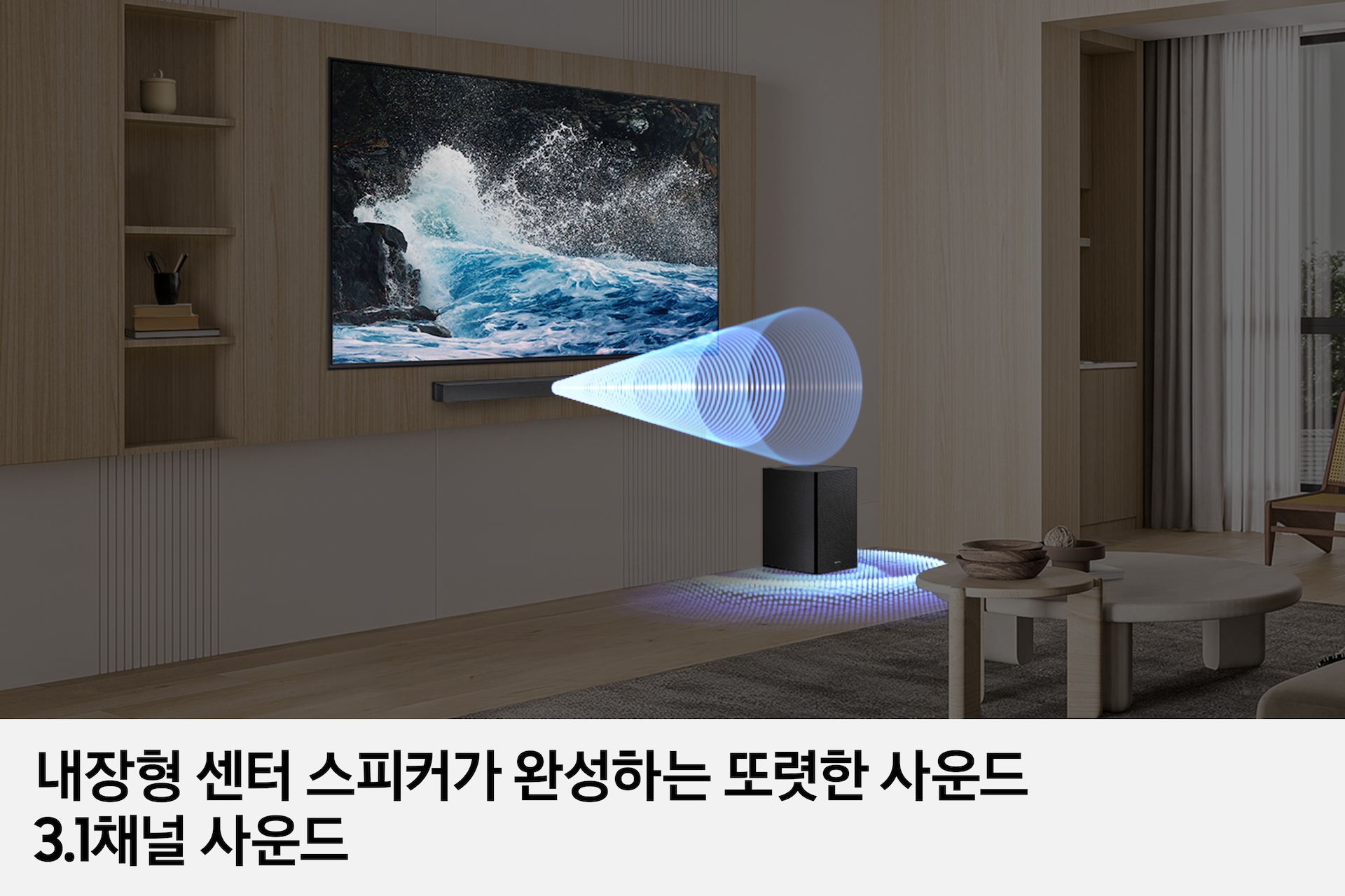 거실 벽에 TV와 사운드바가 놓여 있으며, 우측 하단에는 서브우퍼가 놓여 있습니다. 사운드바와 서브우퍼에서는 음향효과가 나오고 있습니다. 이미지 하단에는 '내장형 센터 스피커가 완성하는 또렷한 사운드 3.1채널 사운드' 문구가 기재되어 있습니다.