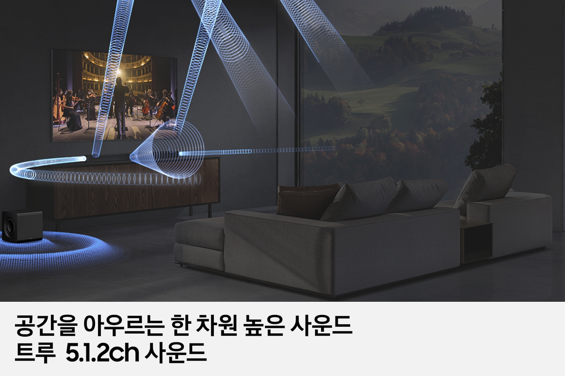 거실 벽에 TV기 설치되어 있으며, 그 아래에는 사운드바 본체가 올라가있는 장식장이 있습니다. 장식장에 왼쪽에는 서브 우퍼가 놓여 있습니다. TV 앞에는 소파와 테이블이 놓여 있습니다. TV 화면에는 첼로와 바이올린을 연주하는 사람들이 보이며, TV 하단에 있는 사운드바에서 음향효과가 나오고 있습니다. 이미지 하단에는 '공간을 아우르는 한 차원 높은 사운드 트루 5.1.2ch 사운드' 문구가 기재되어 있습니다.
