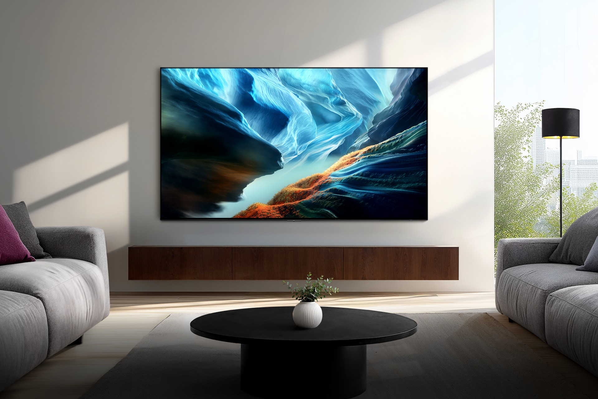 거실 벽에 TV가 설치되어 있습니다. TV 하단에는 화분들이 놓여 있습니다. TV 앞에는 책들이 올려진 테이블과 소파들이 있습니다.