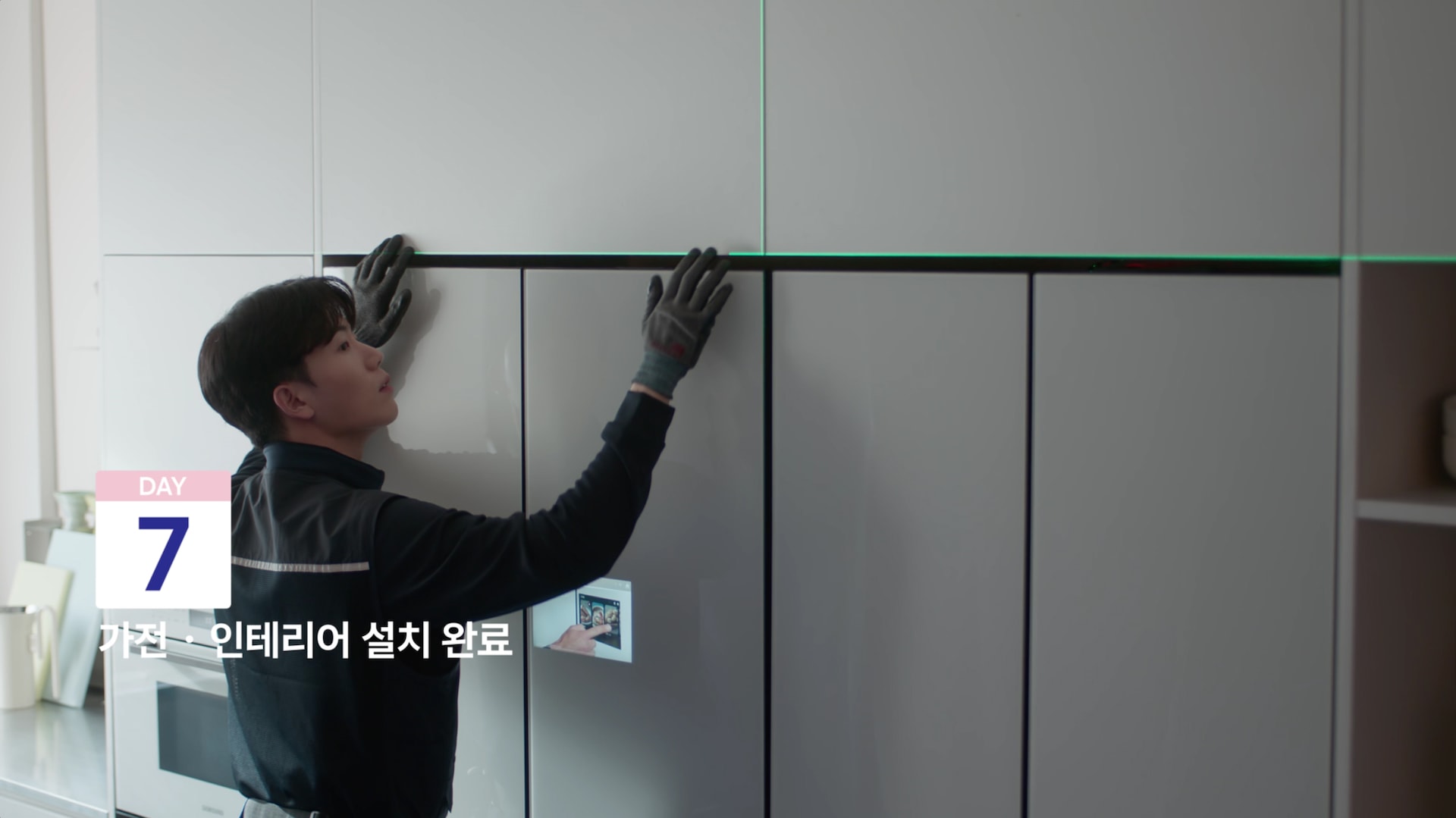 설치 기사가 주방 냉장고장에 냉장고를 설치하고 있습니다.