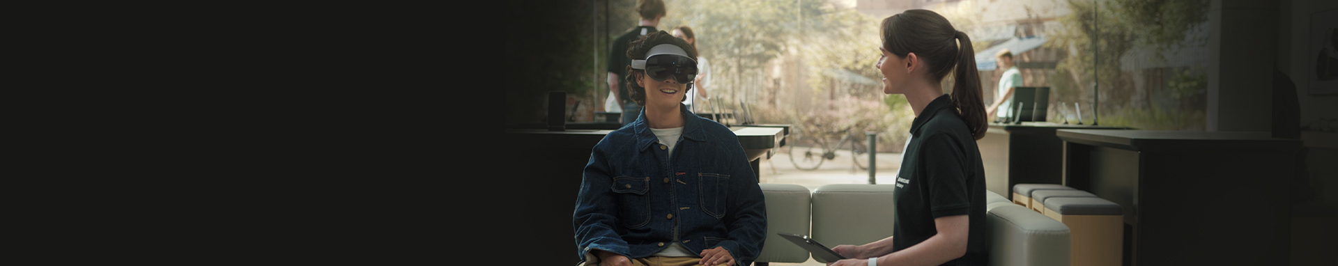 갤럭시 XR을 착용한 남성과 옆에서 사용법을 안내하는 여성이 있습니다.