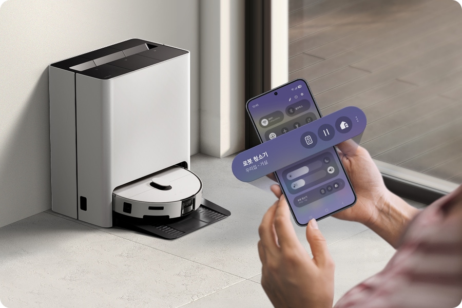 한 사람이 스마트폰을 들고 Bespoke AI 스팀 앞에 서 있습니다. 스마트폰 화면 위로 원격, 시작, 홈 에너지 아이콘이 있는 위젯이 확대되어 겹쳐 나타납니다.