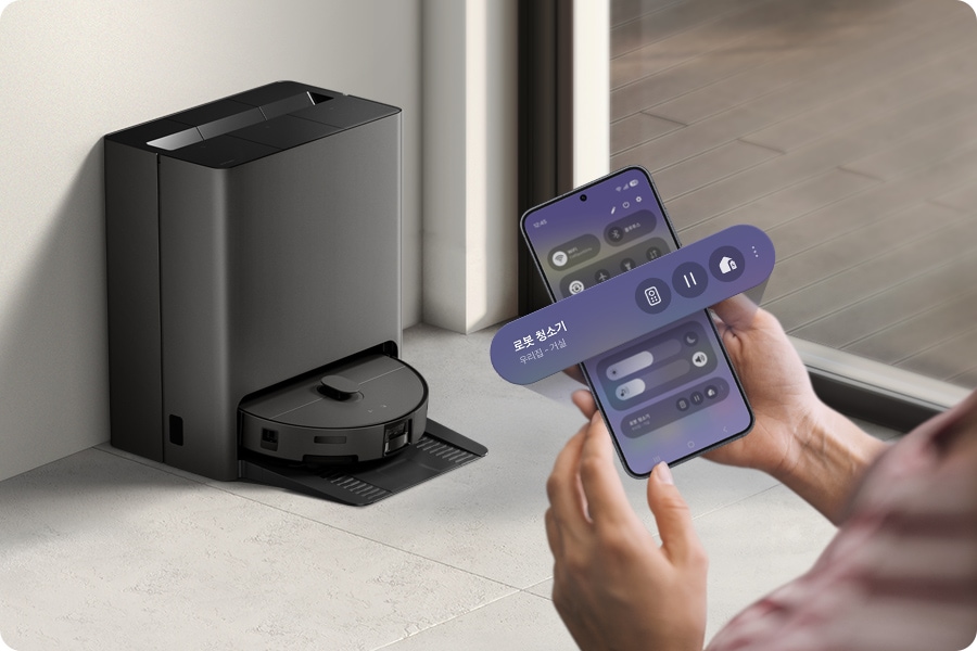 한 사람이 스마트폰을 들고 Bespoke AI 스팀 앞에 서 있습니다. 스마트폰 화면 위로 원격, 시작, 홈 에너지 아이콘이 있는 위젯이 확대되어 겹쳐 나타납니다.