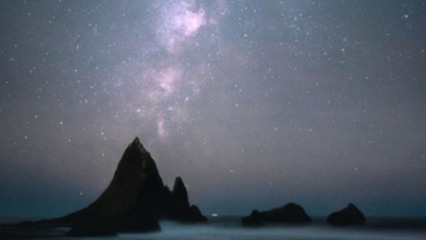 별이 빛나는 밤하늘 아래에서 촬영한 해변과 바위 사진이 있습니다.