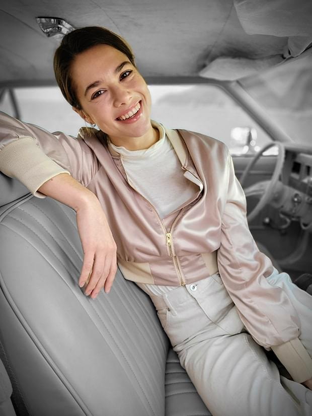 Foto de una mujer sentada en el asiento del conductor tomada en modo Retrato con efecto Punto de color aplicado.