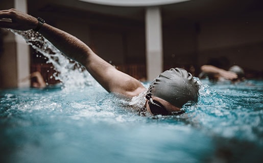 Una persona está nadando en una piscina mientras usa un dispositivo Galaxy Watch4 Classic.