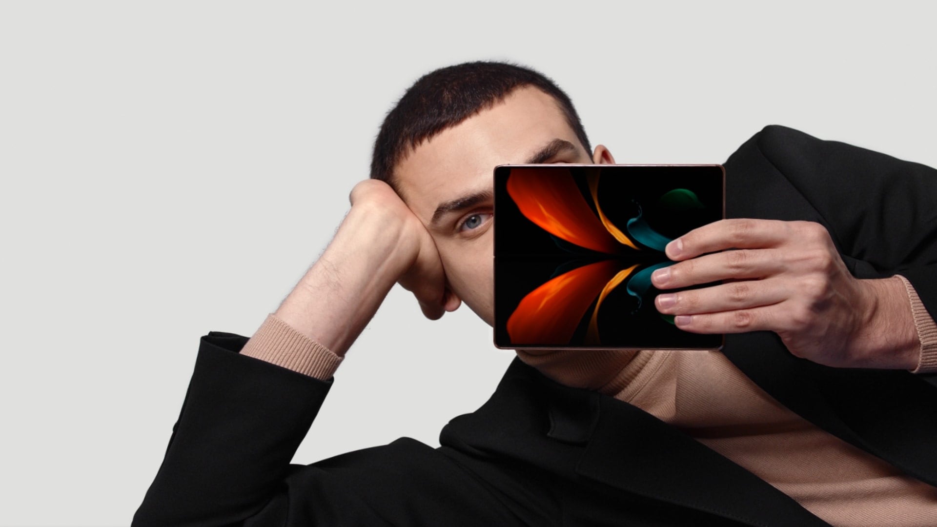 A man holding Galaxy Z Fold2 unfolded and seen from the side. He turns it to show the Main Screen, with the butterfly wallpaper oncreen.
