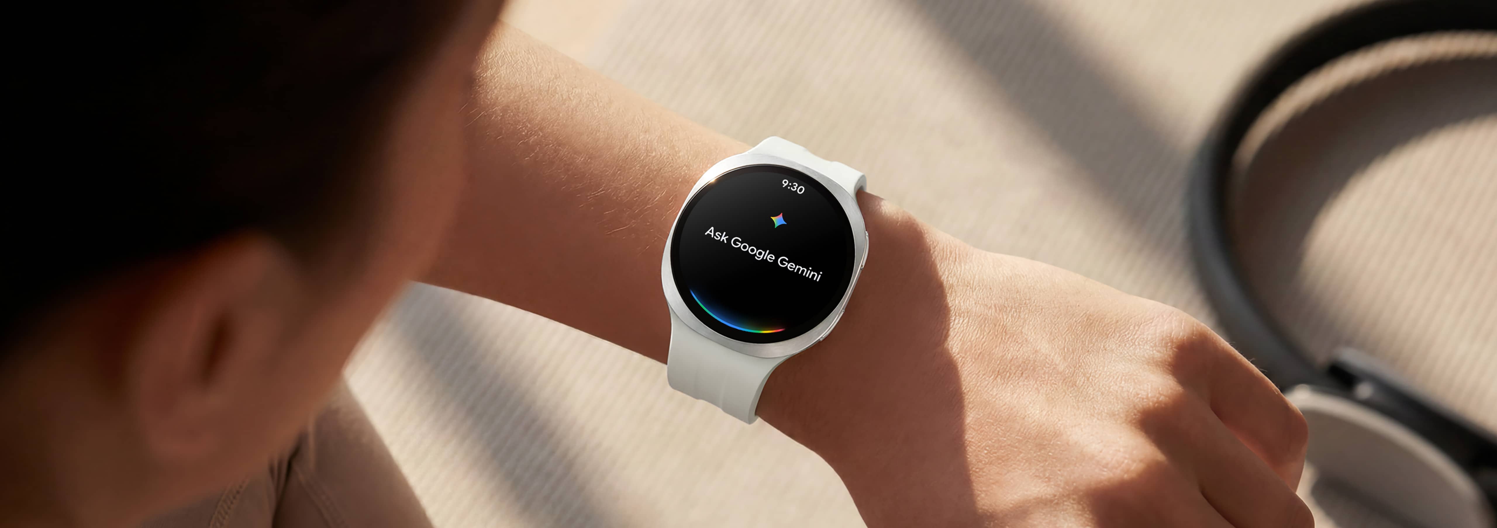 شخص يرتدي ساعة Galaxy Watch9 باللون الكريمي مع حزام رياضي باللون الكريمي، ويرفع معصمه لإصدار أمر صوتي لساعته باستخدام تطبيق Google Gemini.