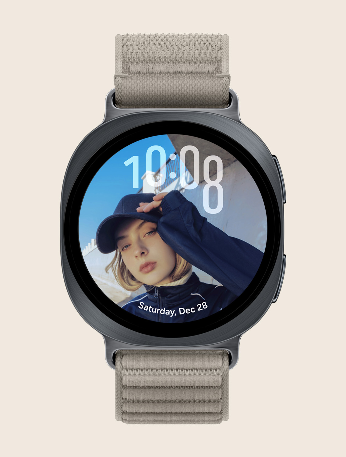 عرض أمامي وعرض زاوية مقرب يُظهِر ساعة Galaxy Watch9 مع حزام قماشي بلون موكا، تظهر واجهة الساعة بالطول مخصصة مع الوقت في الأعلى والتاريخ في الأسفل، دون تداخل مع وجه الشخص.