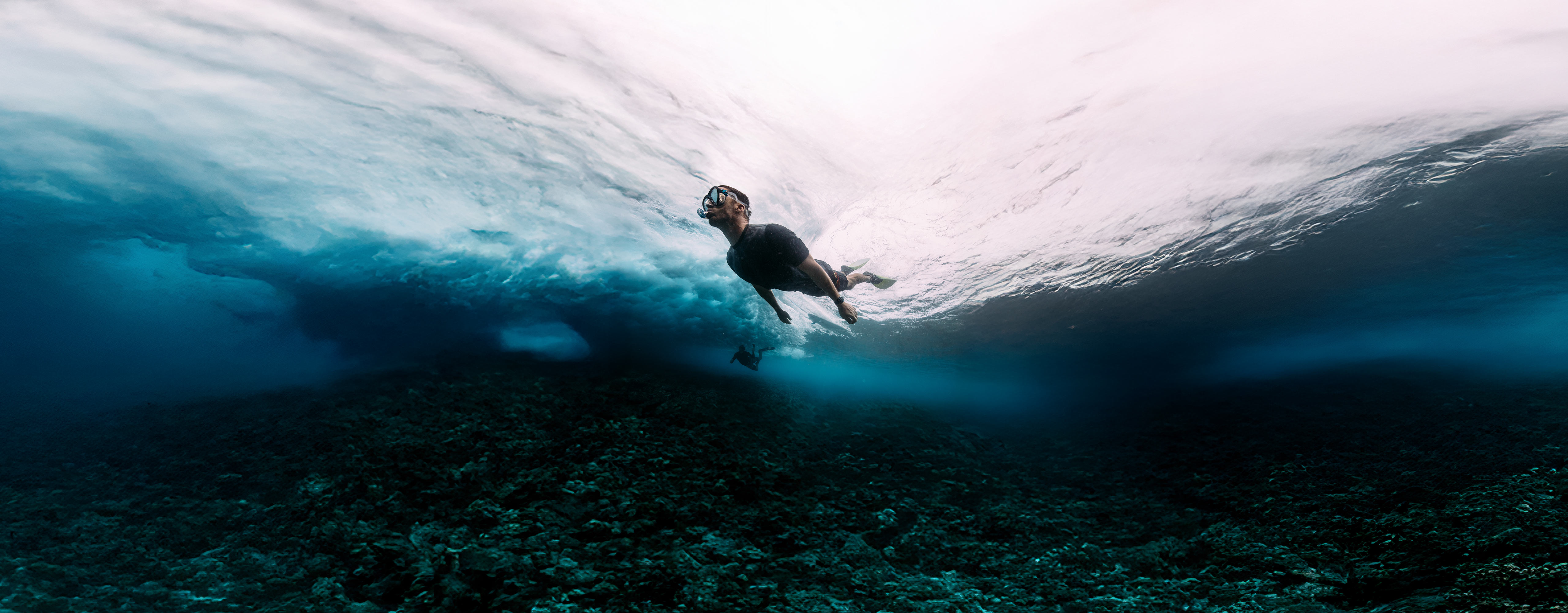 A man in a swimsuit is swimming in the ocean, with a Galaxy Watch Ultra on his wrist.