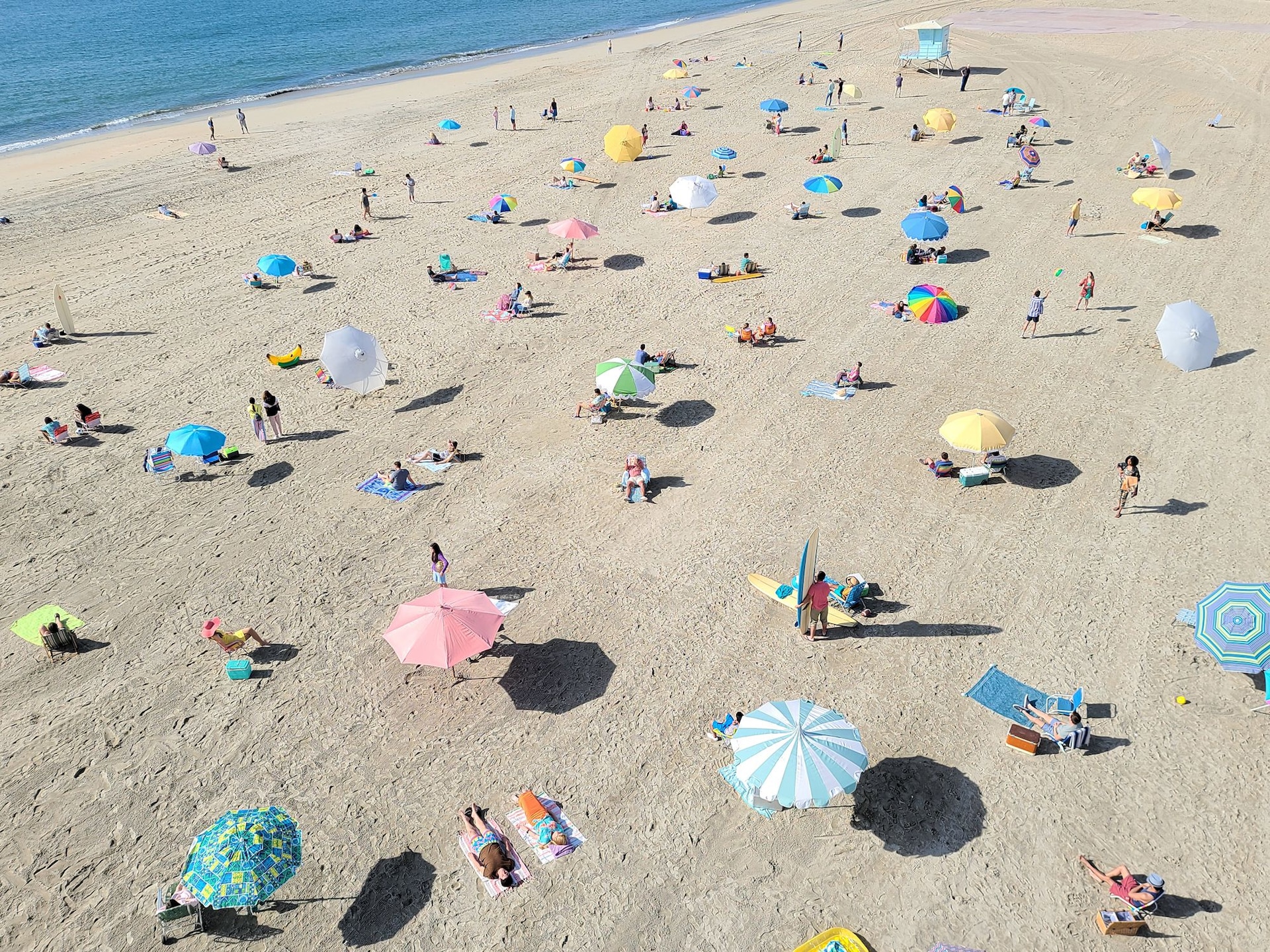 Photo taken on Galaxy S20 Ultra of a beach with many people. As we zoom in on the photo, we see a funny moment of someone lounging on a beach chair with a magazine in front of their face that says “GOT-YA!”, showing how Space Zoom lets you find moments you might have otherwise missed