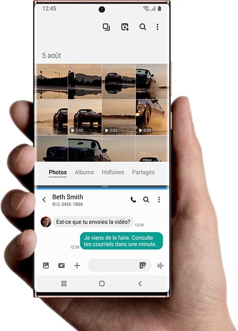Un téléphone Galaxy Note20 Ultra devant un téléviseur, connecté sans fil via Samsung DeX. Sur l’écran du téléviseur, on voit un lecteur vidéo qui joue le film de voitures roulant sur une route recouverte d’eau. L’application d’e-mail est également ouverte, avec en objet Vidéo FINALE. Sur l’écran du téléphone se trouve l’application Galerie, qui montre des miniatures de la vidéo vue sur le téléviseur, et son écran est scindé avec l’application Messages. Il y a un message texte avec Beth Smith, qui dit « Tu envoies la vidéo ? » Et la réponse : « Je viens de terminer. Vérifie tes e-mails dans une minute. »