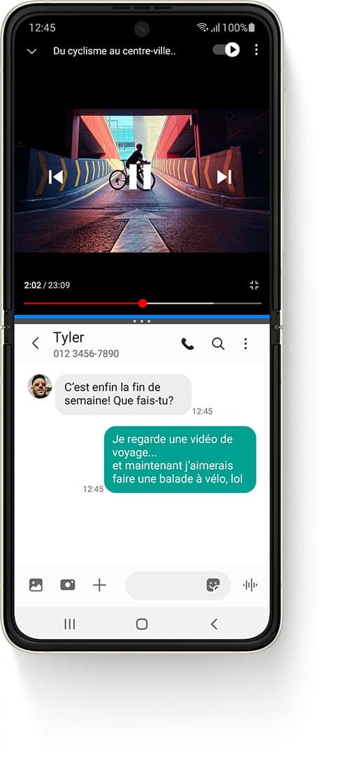 Le Galaxy Z Flip3 5G est déplié avec la fenêtre multiactive, montrant une vidéo YouTube en haut, une vidéo intitulée Cycling Through Downtown et une personne debout sur un vélo sur une rampe. L'application Messages en bas et le message texte reçu de Tyler dit "C'est enfin le week-end ! Que fais-tu ?" Le message texte envoyé dit "Je regarde une vidéo de voyage... et maintenant je veux faire un tour de vélo, lol"