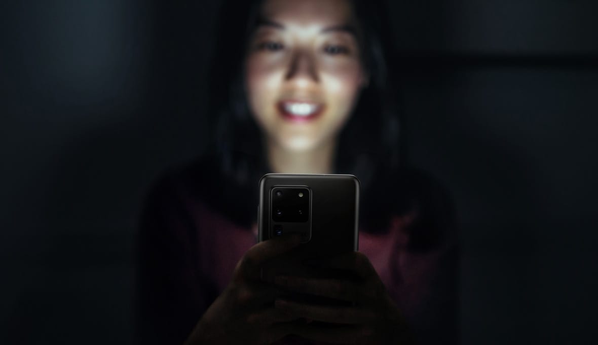 A woman using her Galaxy S20 Ultra and smiling because it’s fast and powerful with the advanced AP and RAM