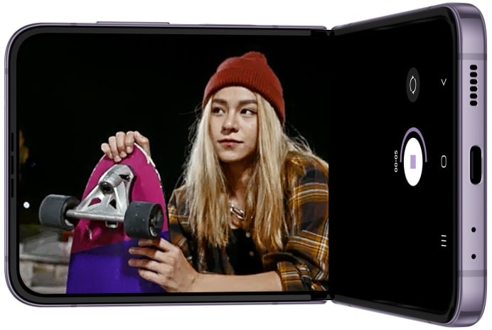 Galaxy Z Flip4 is seen in Flex mode. On the Main Screen, the camera app is seen recording a video of skateboarders at night. The subjects are clear and the video is smooth, even in low light.