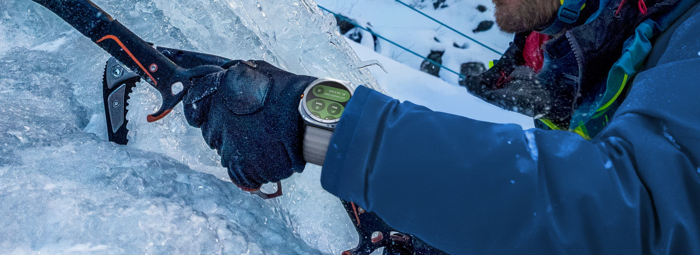 Prim-plan al unei persoane care se tine de un echipament pentru escaladare pe gheata, cu Galaxy Watch Ultra pe incheietura.