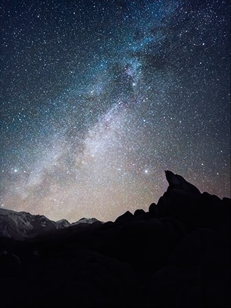 Fotografija noćnog pejzaža sa obrisom planinskog terena u prvom planu. Detalji zvezdanog neba su jasno uhvaćeni kao detalji visoke rezolucije pomoću Expert Raw. Fotografija je snimljena telefonom Galaxy S23 Ultra koristeći široki režim sa otvorom blende F 1.7.