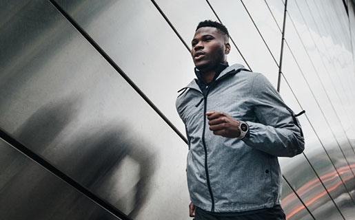 A man is running outdoors while wearing a Galaxy Watch4 Classic device.