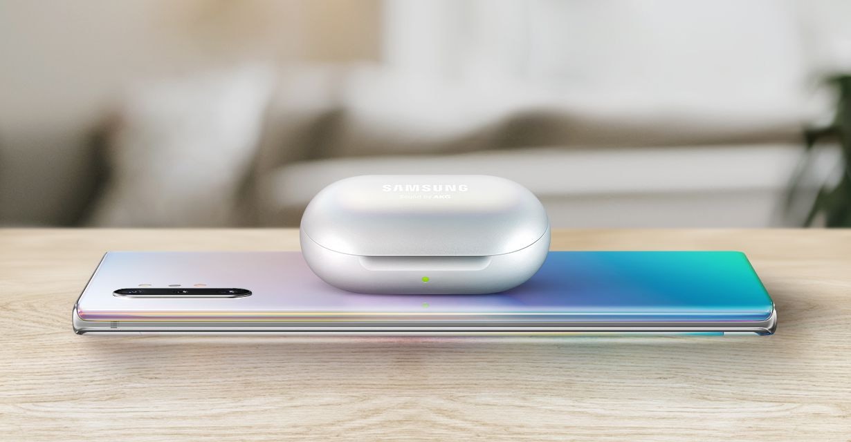 Galaxy Note10 plus laying facedown on a table with Galaxy Buds charging on top via Wireless PowerShare