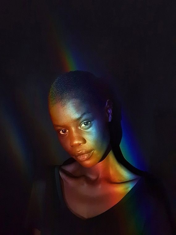 Selfie captured by Galaxy S10 plus of a woman in a low-light space with a rainbow light glowing across her face.