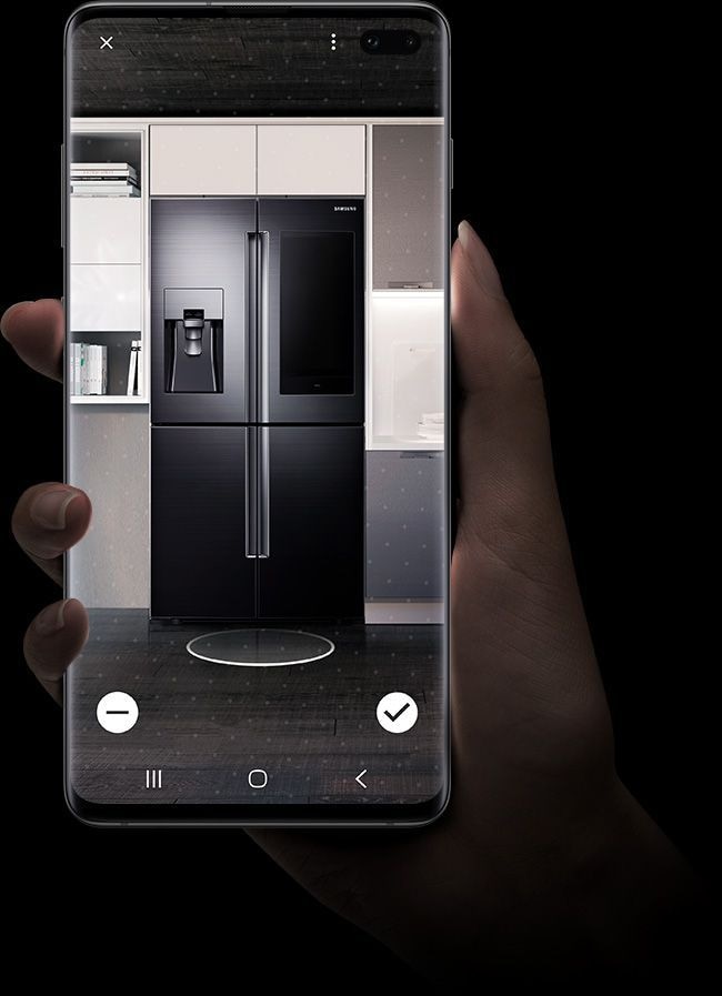Image of a hand holding Galaxy S10 plus with Bixby Visionâs Apps mode Home Decor feature onscreen. Itâs showing a Samsung refrigerator in a kitchen.