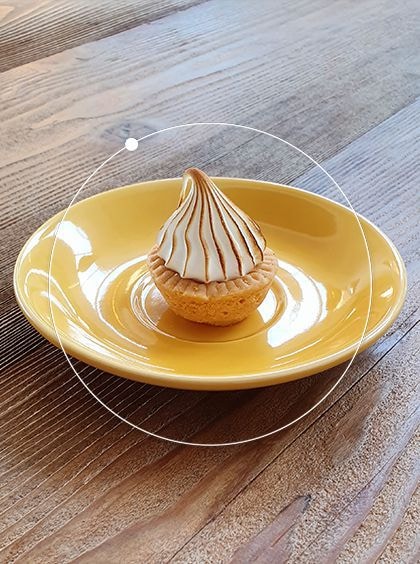 Photo captured by Galaxy S10 plus of a pastry on a yellow plate. Overlaid is a circle to represent Bixby Vision detecting the item.