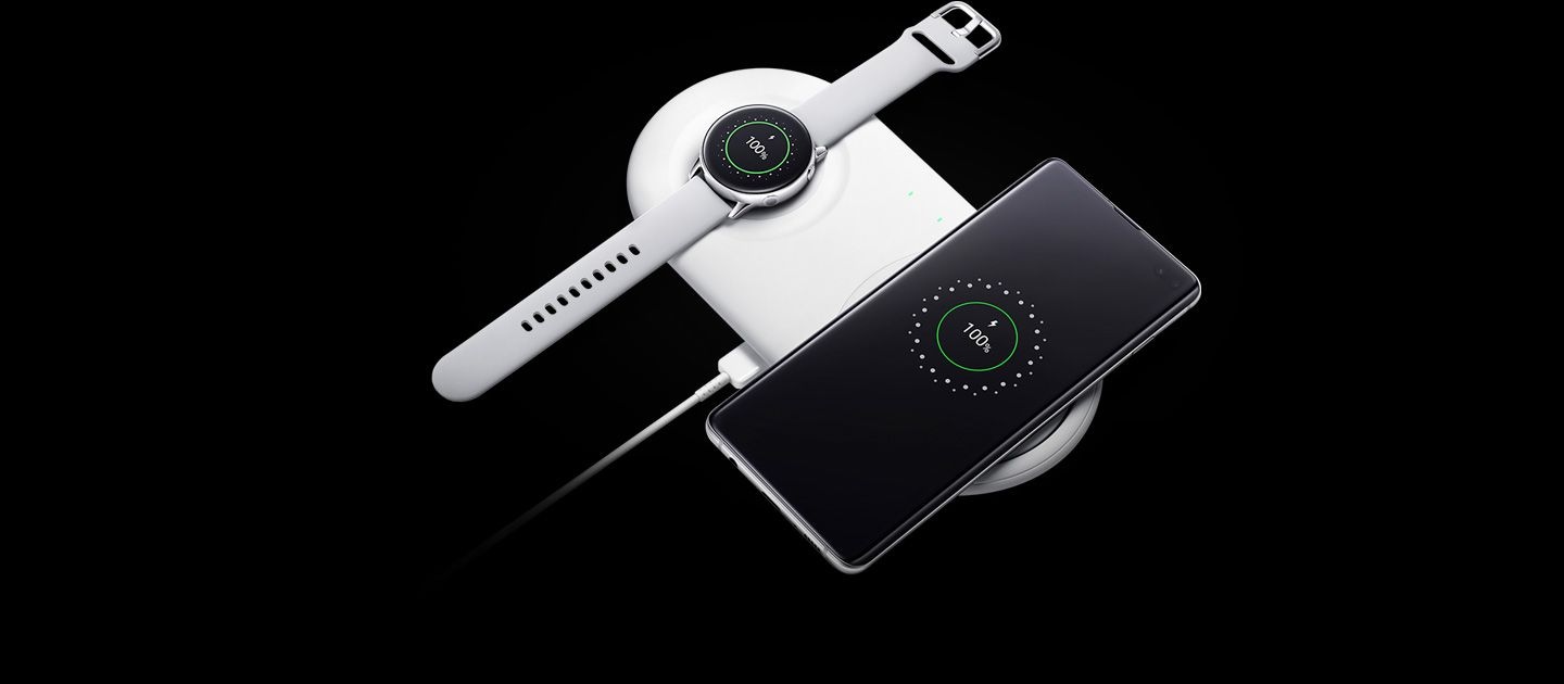 صورة تظهر شحن ساعة Galaxy Watch Active مع هاتف Galaxy S10 plus على قاعدة الشاحن اللاسلكي المزدوج، مع عرض واجهة الشحن على شاشتي الجهازين.