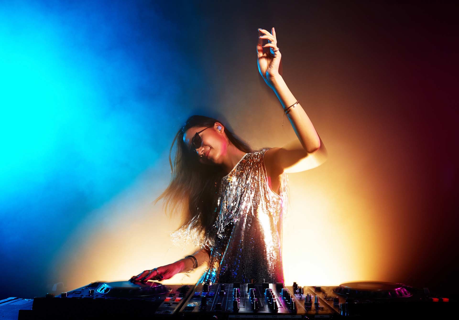 A female DJ seen DJing with Samsung Galaxy Buds2 Pro in Bora Purple on her left ear with her right hand on the mixer