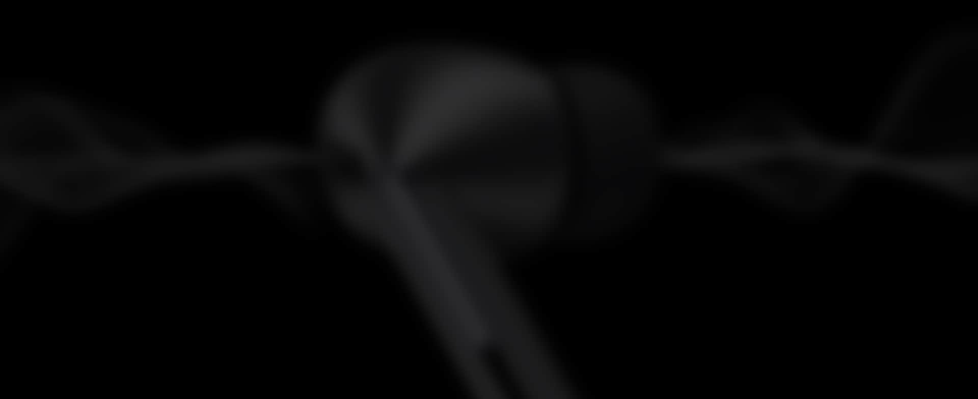 The image showcases a close-up view of sleek, black Samsung Galaxy Buds3, partially obscured by an abstract background. The modern design emphasizes the curves and shapes of the Buds3 against a dark backdrop, reflecting sophisticated audio quality.