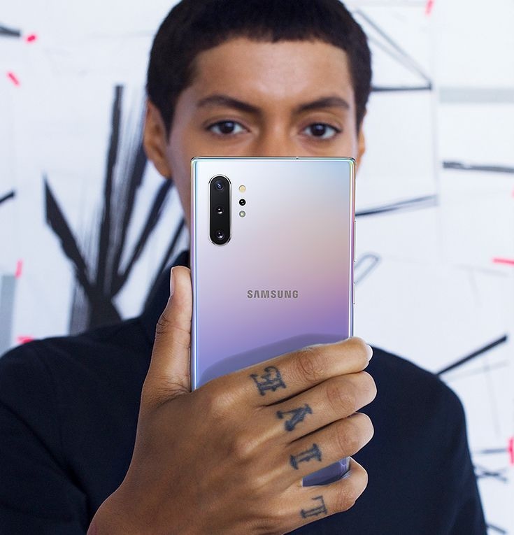 Man holding and looking at his Galaxy Note10+ as he uses Face Recognition to unlock his phone