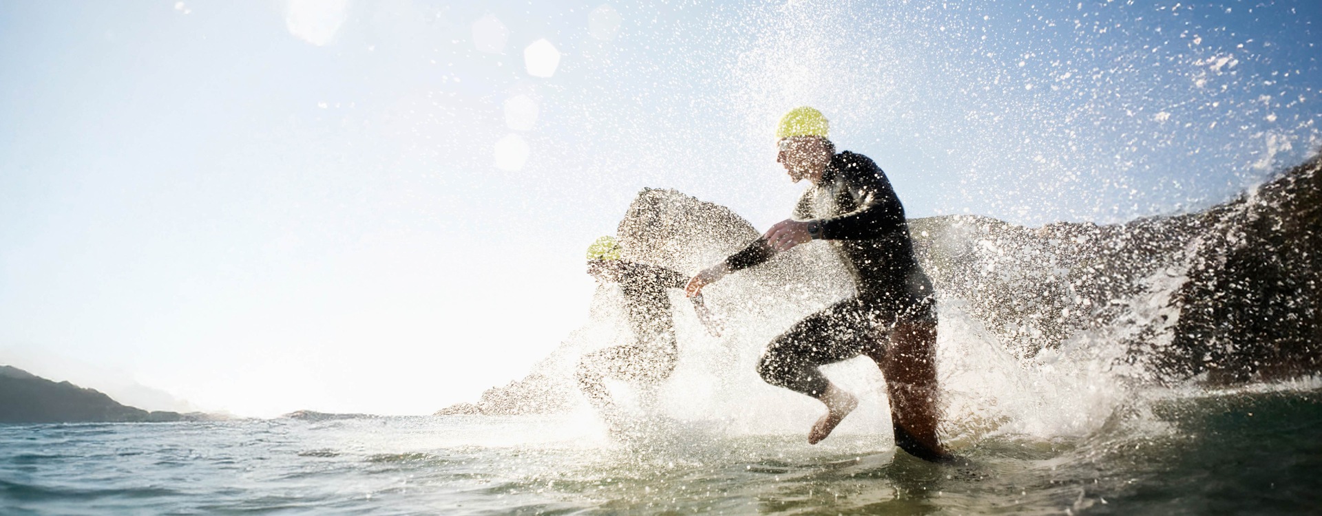 Two people in swimsuits are jumping into the water. The person in the front has Galaxy Watch Ultra on the wrist.