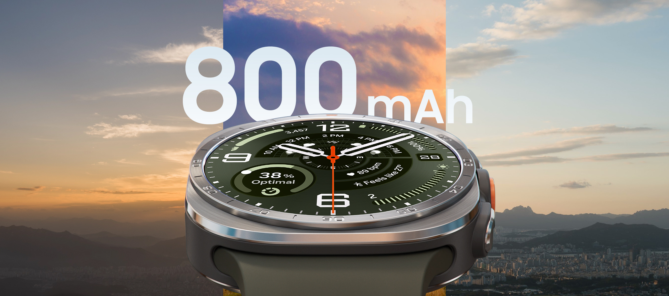 Galaxy Watch Ultra2 in Titanium Silver with a Marine Band in Olive, shown up close facing front and angled upward. The background shows three different skyline and cityscape views at different times of day to demonstrate the large 800 mAh battery capacity.