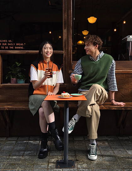 A color rich photo of two people sitting in front of a cafe taken at 2x zoom.