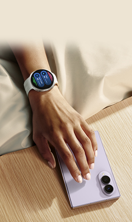 Someone is reaching for a folded Galaxy Z Fold8 in Lavender. They are wearing Galaxy Watch9.