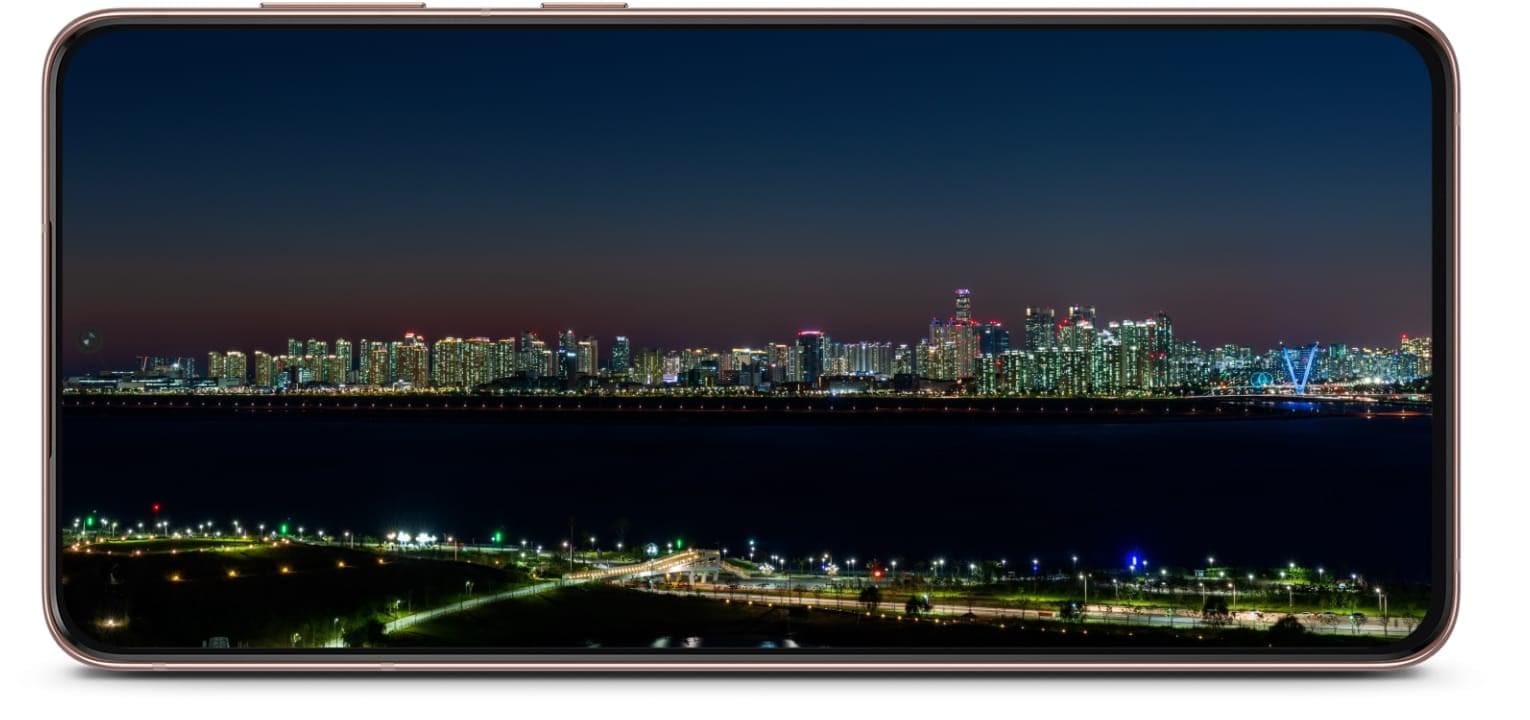 Galaxy S21 Plus 5G phone seen from the front in landscape view with a cityscape onscreen. The cityscape lighting goes from day to night to demonstrate using the phone from morning until night.