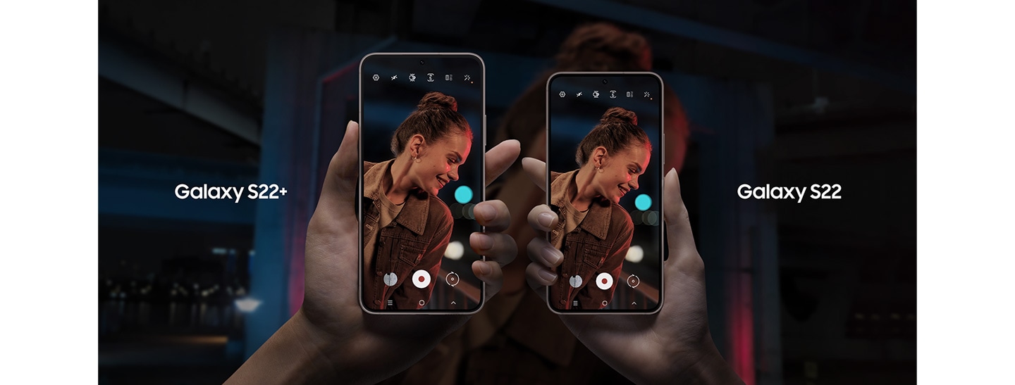 A Galaxy S22+ and a Galaxy S22 are being held up in the center of the banner by two hands facing towards each other, with the Galaxy S22+ on the left and the Galaxy S22 to the right. On each of the device screens is an image of a woman smiling while she is being filmed during a night scene, which also makes up the background. The title of each device is above them. 