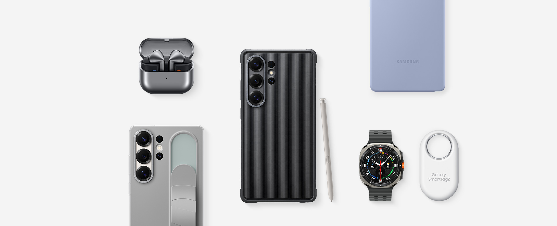 A flat lay of Samsung accessories for Galaxy S25 Ultra: First, Galaxy Buds3 Pro in Silver with the ear buds, Galaxy S25 Ultra with Rugged Case installed and S Pen in Light Gray, Galaxy S25 Ultra with Silicone Case in Light Blue installed, SmartTag2 in White, Galaxy Watch Ultra in Titanium Silver, Galaxy S25 Ultra with Standing Grip Case in Gray installed.