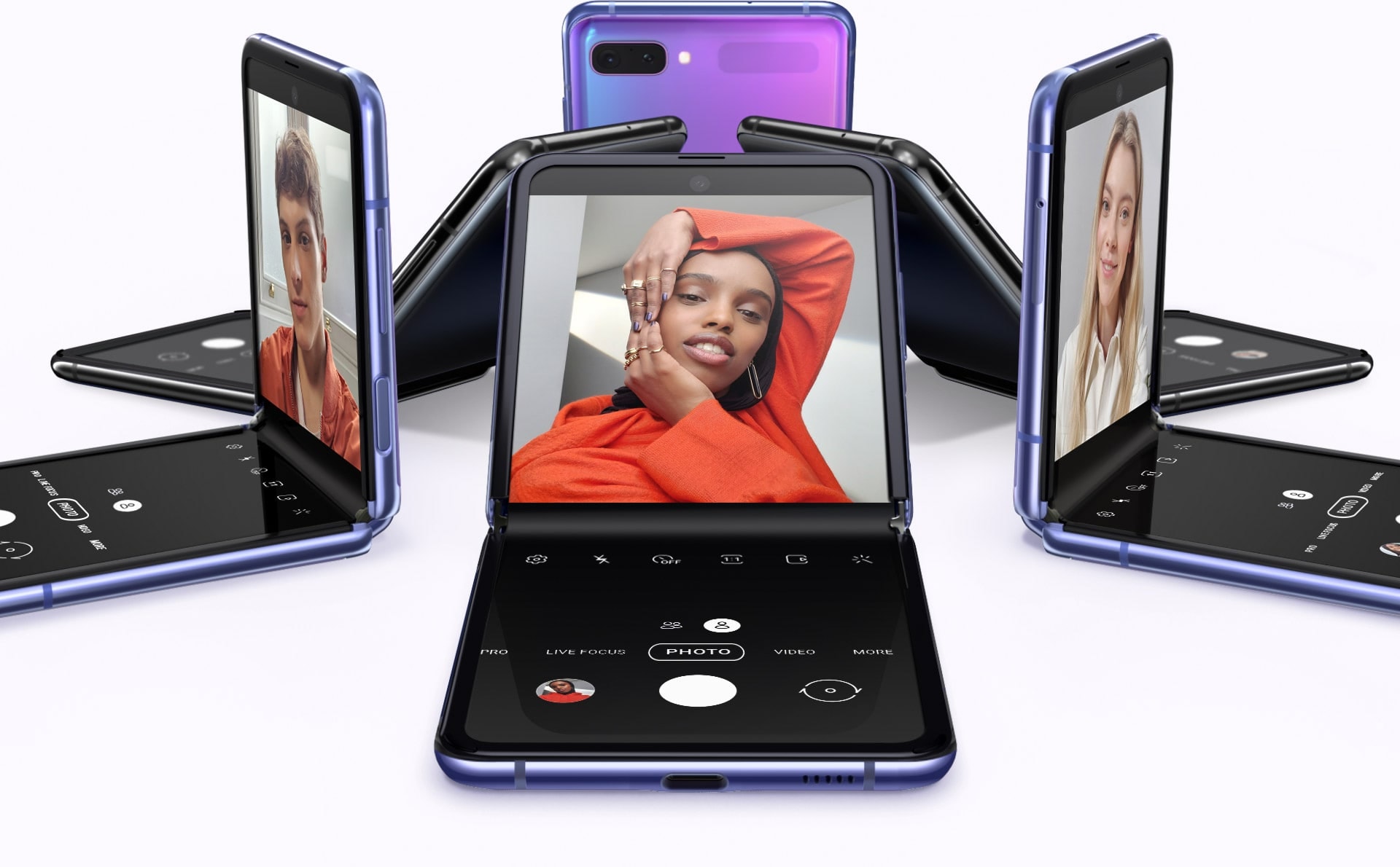 Six Galaxy Z Flip phones in Mirror Purple and Mirror Black in a circle at various angles. One has a selfie of a man, another has a selfie of a woman, and another has a different selfie of a woman on screen
